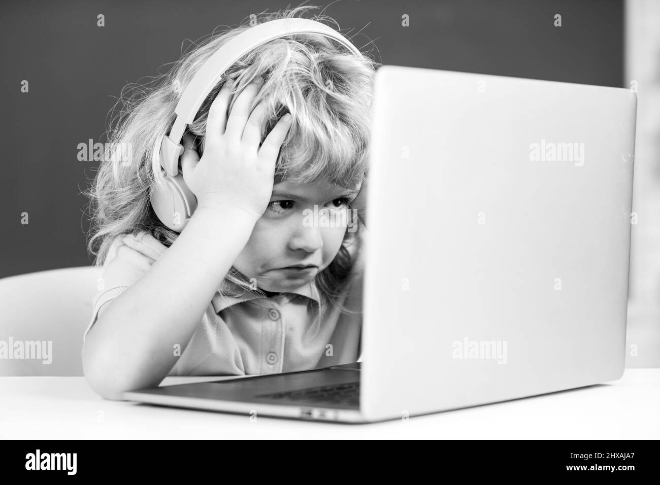 Angry sad school kid working in computer class. Little funny system administrator or programmer. Stock Photo