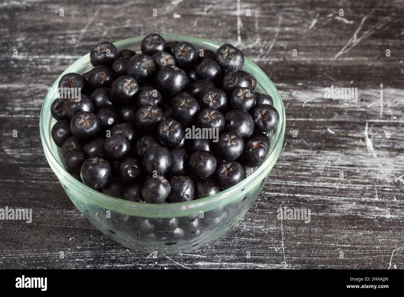 Close up chokeberries in glass bowl on the black background Stock Photo