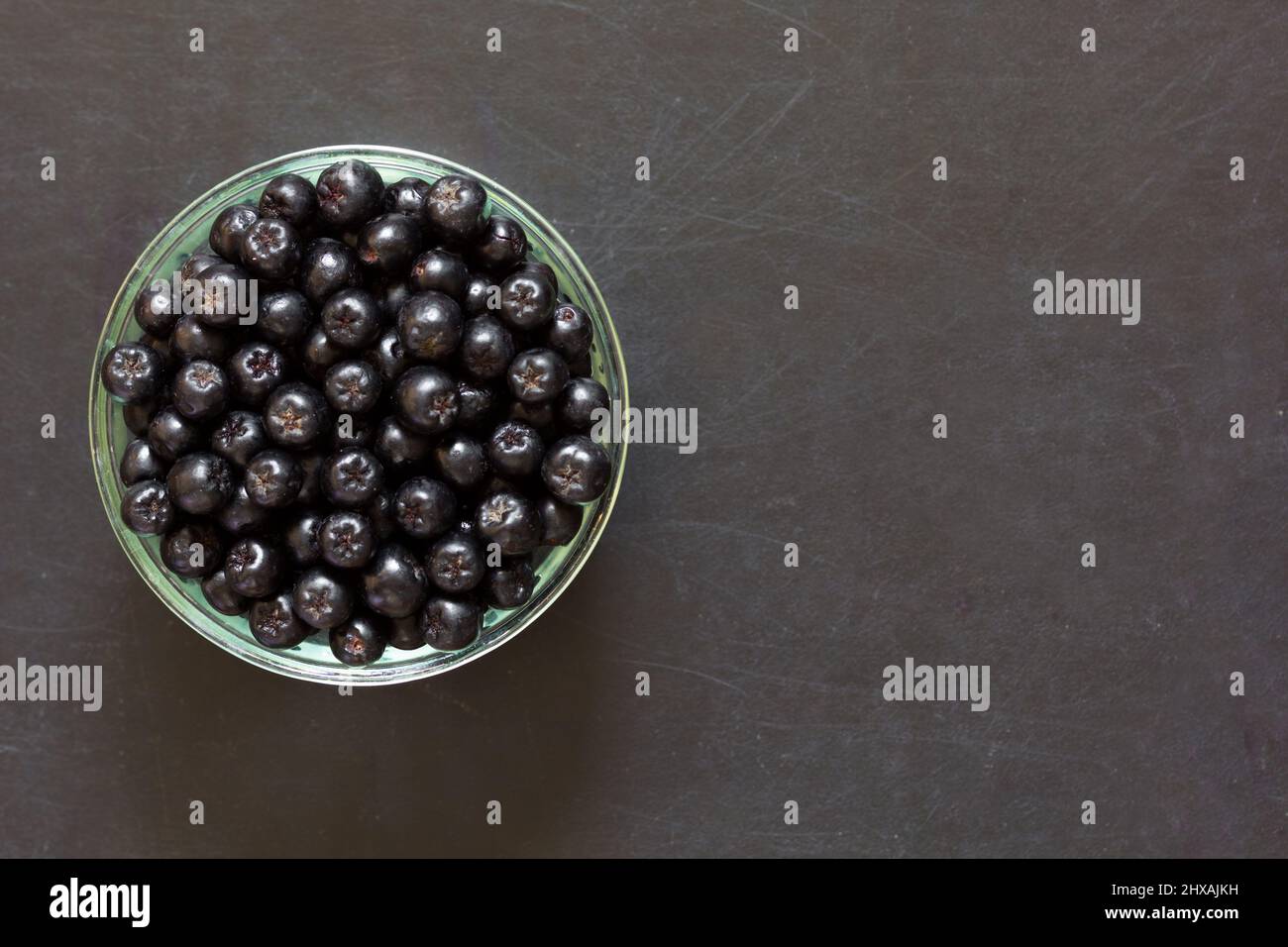 Top view of chokeberries in glass bowl on the black background Stock Photo