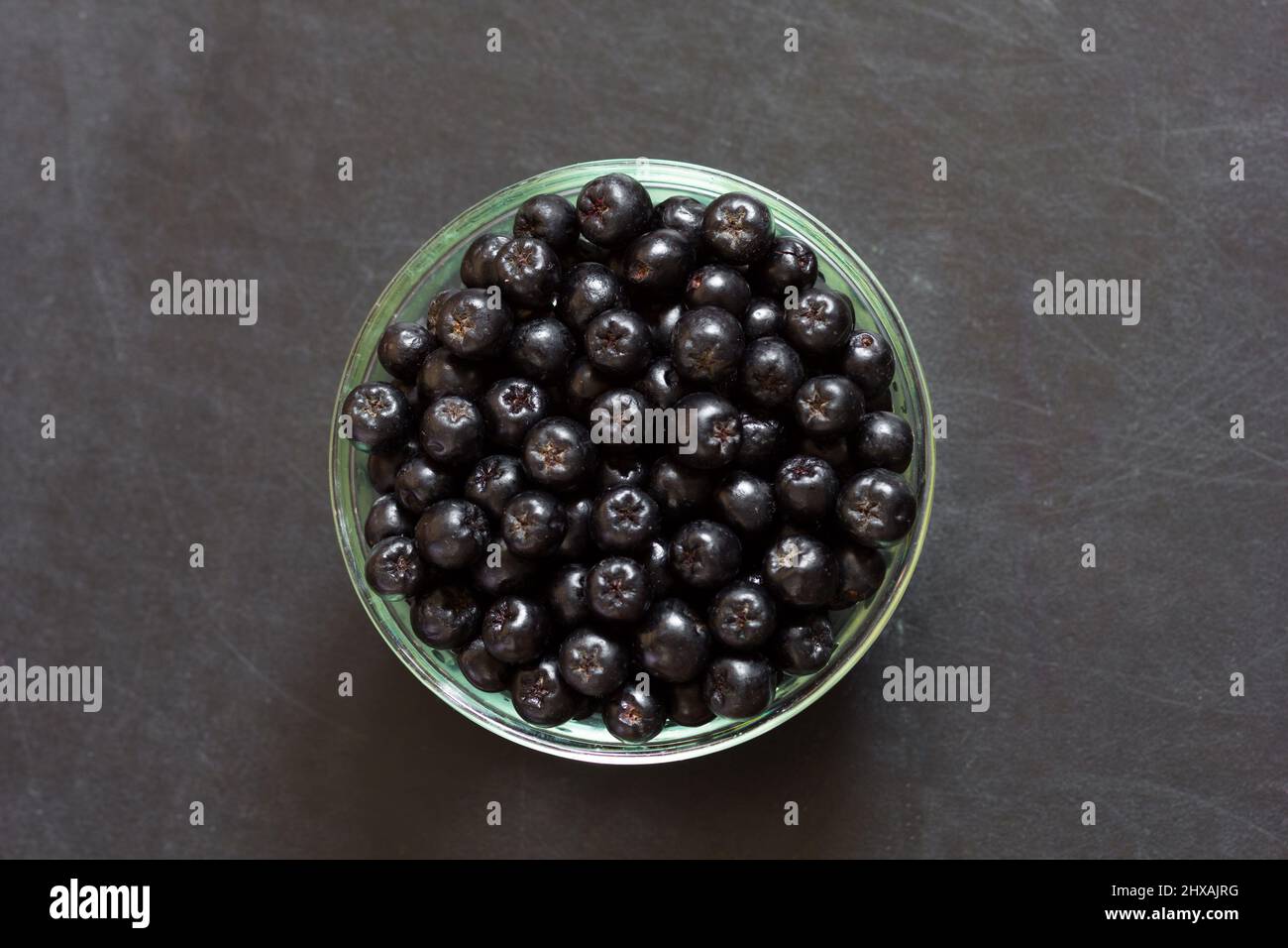 Top view of chokeberries in glass bowl on the black background Stock Photo