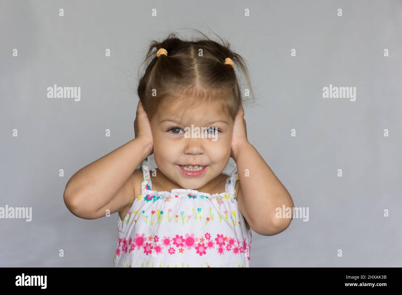 Smiling child does not want to hear anything closing ears by hands Stock Photo