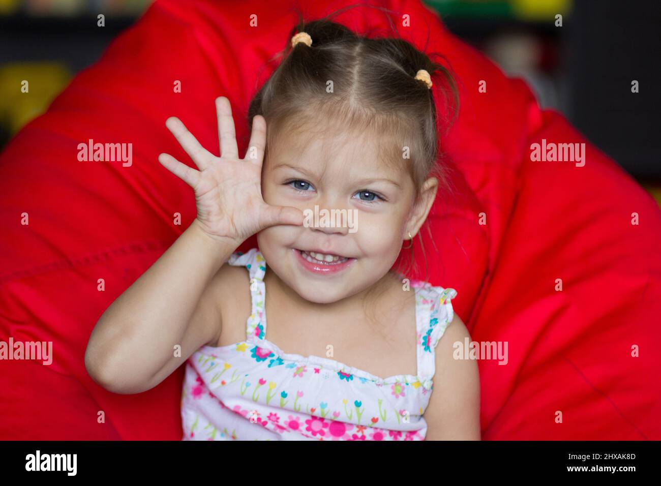 Portrait of cute child showing five sitting on the red armchair pear Stock Photo