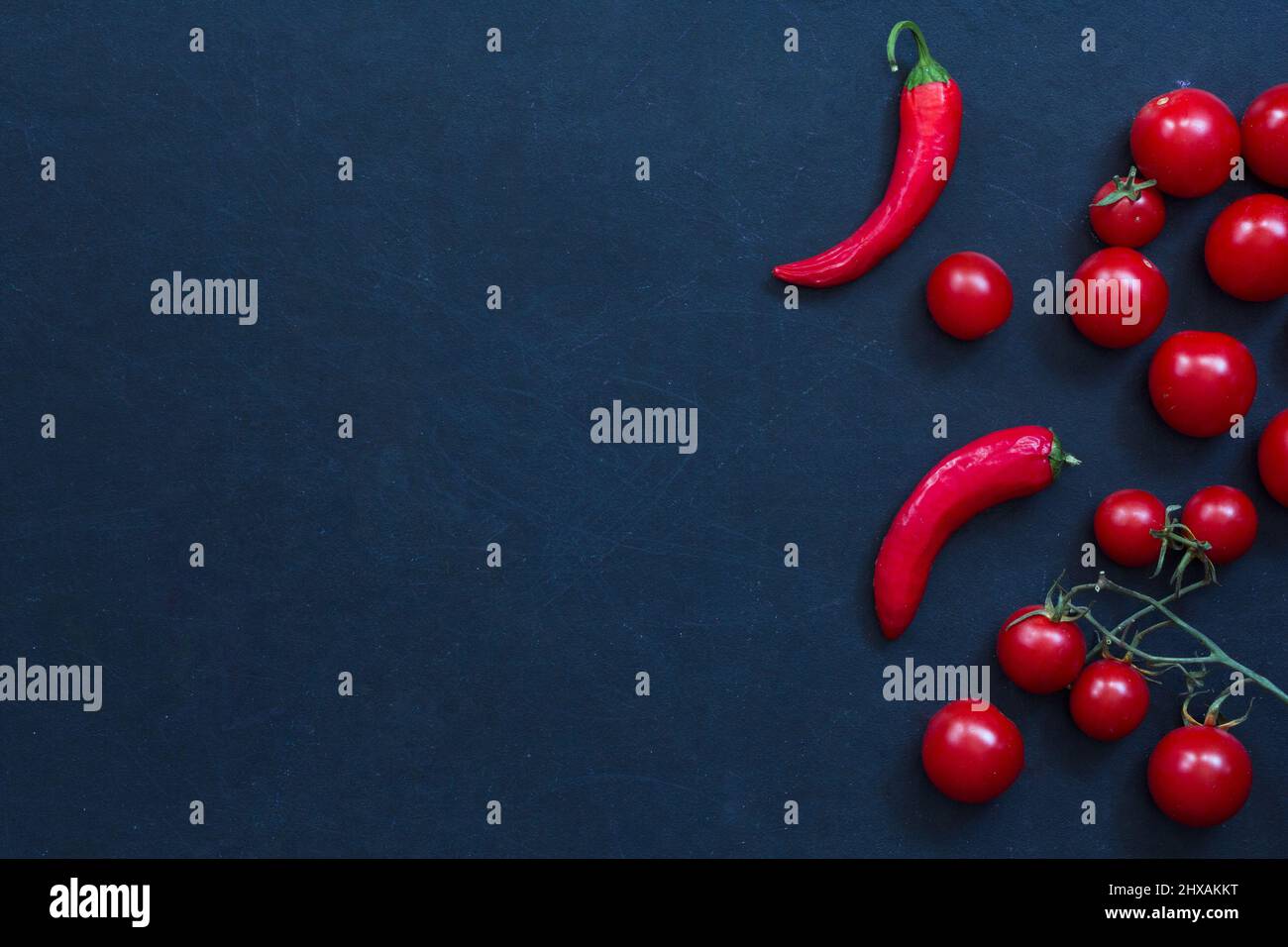 Fresh chilli peppers and tomatoes cherry on the black background Stock Photo