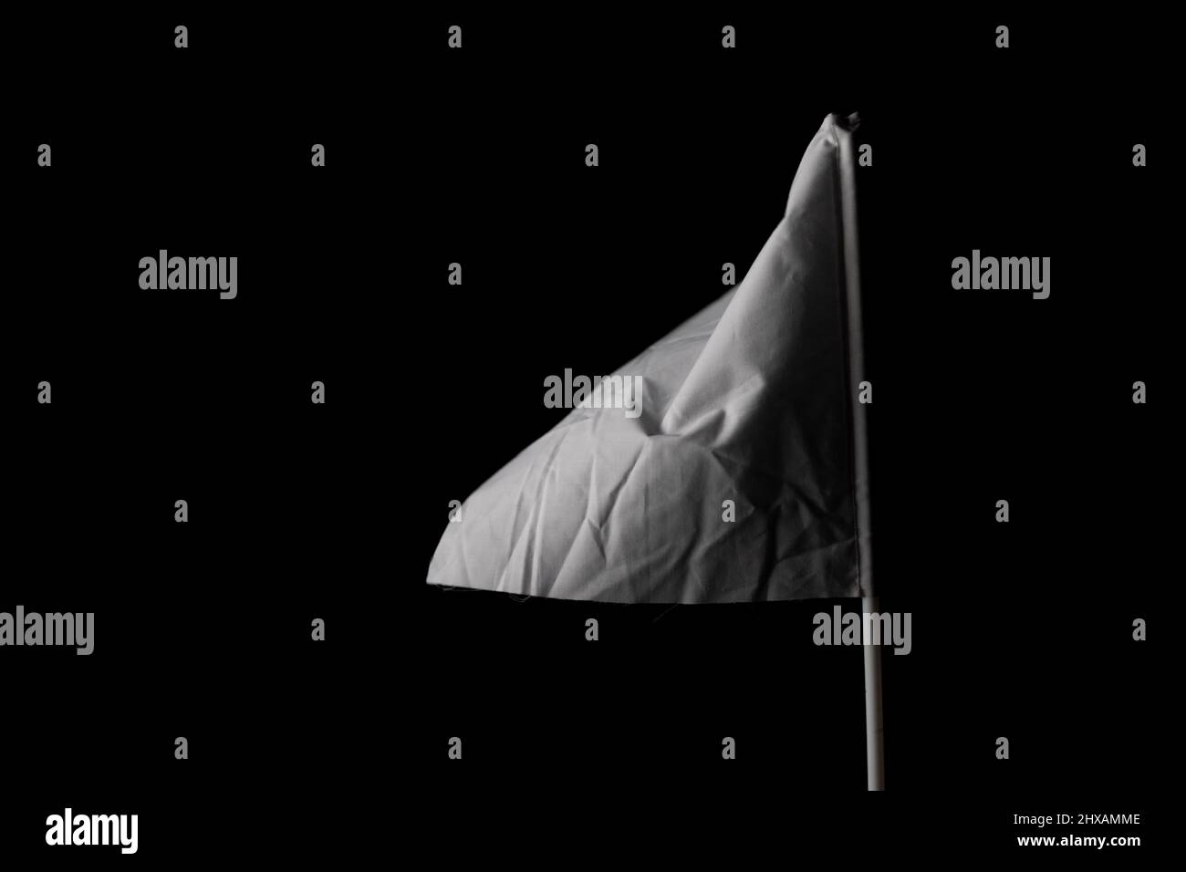 High ISO images of waving White flag on dark background with copy space - concept of symbol of peace, activist and demonstration. Stock Photo