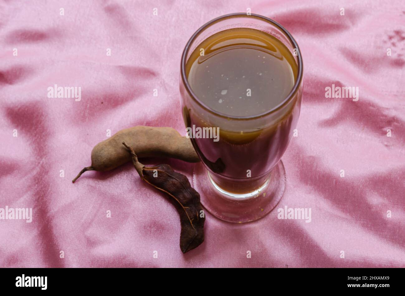 Drinking Glass With Tamarind Juice On Pink Background Stock Photo