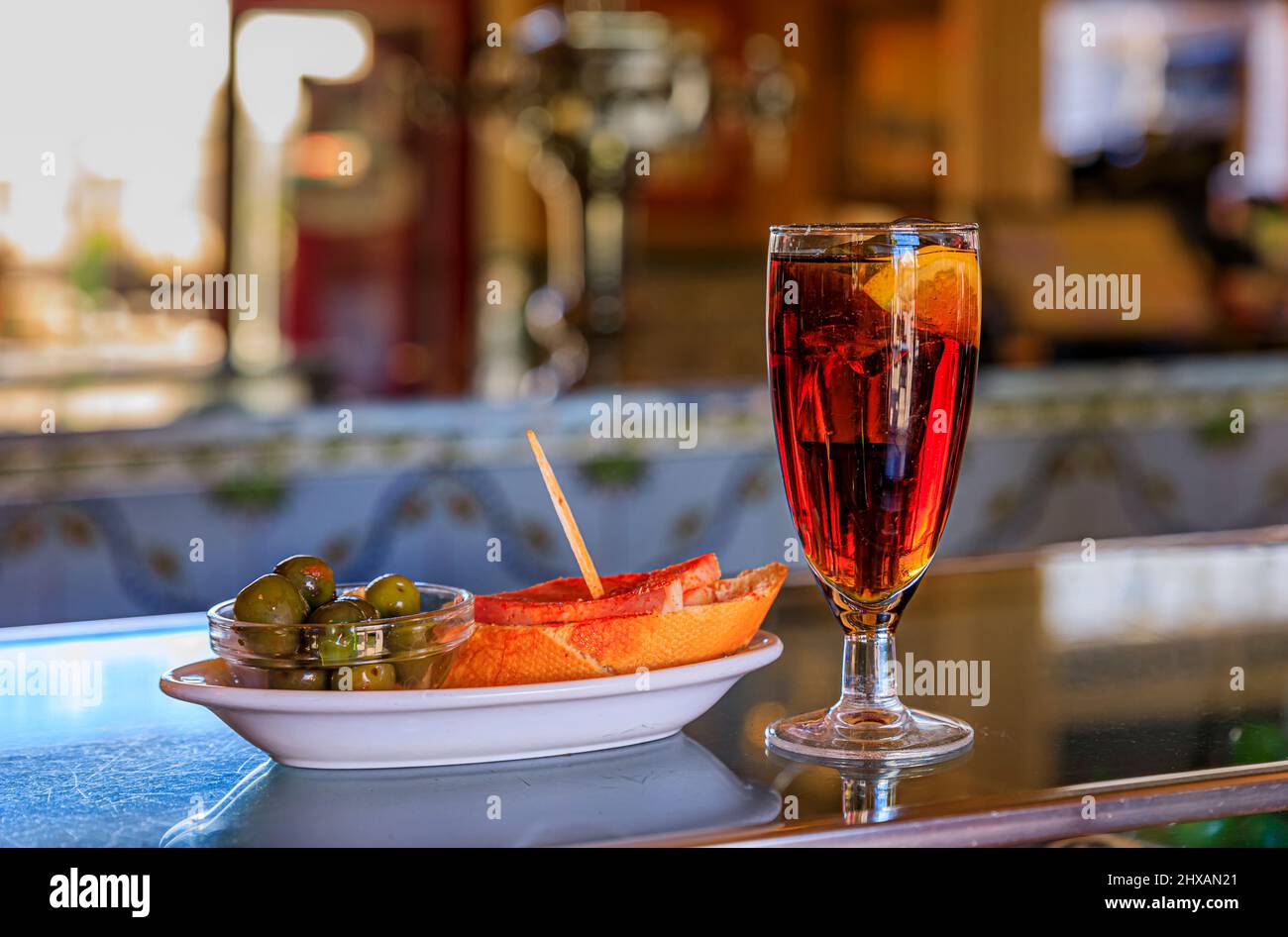 Traditional Spanish tapas of green olives and a jamon cured ham sandwich with a cocktail on a bar counter at a bar in Madrid, Spain Stock Photo