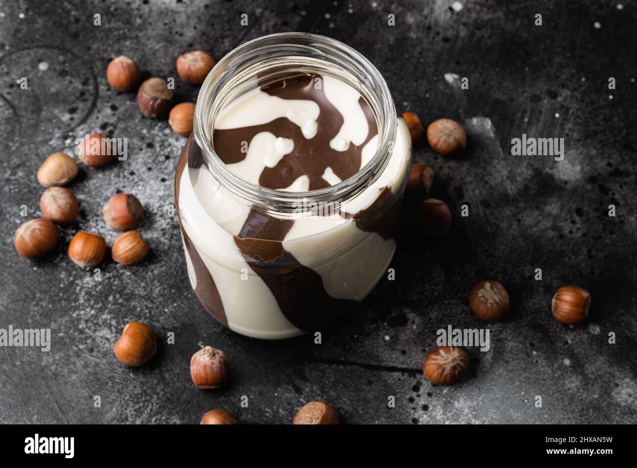 Hazelnut spread with nuts set, on black dark stone table background Stock Photo