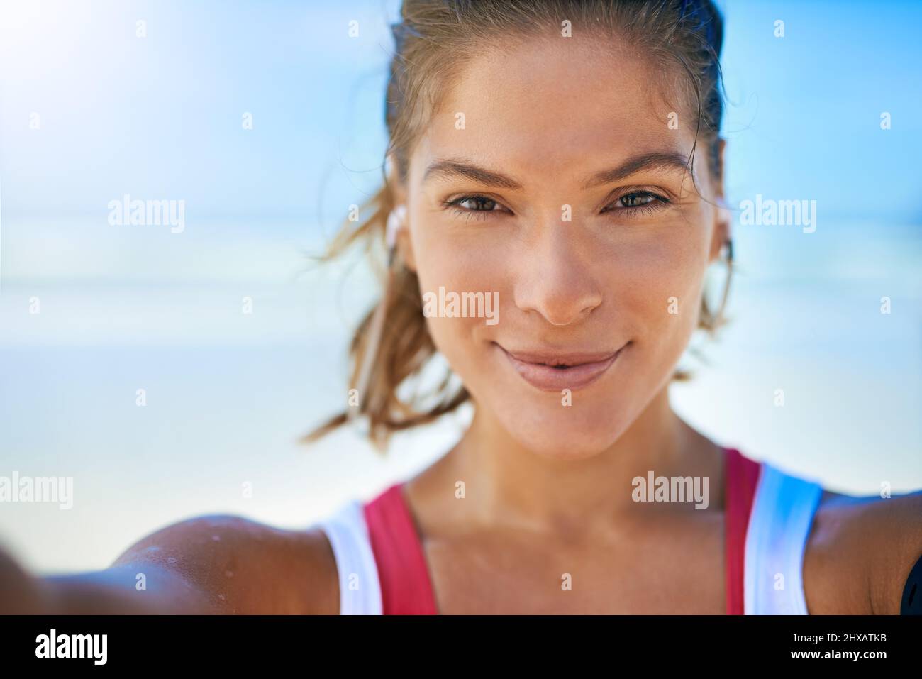 Selfies to show my progress. Shot of a young woman taking a selfie while working out on the beach. Stock Photo