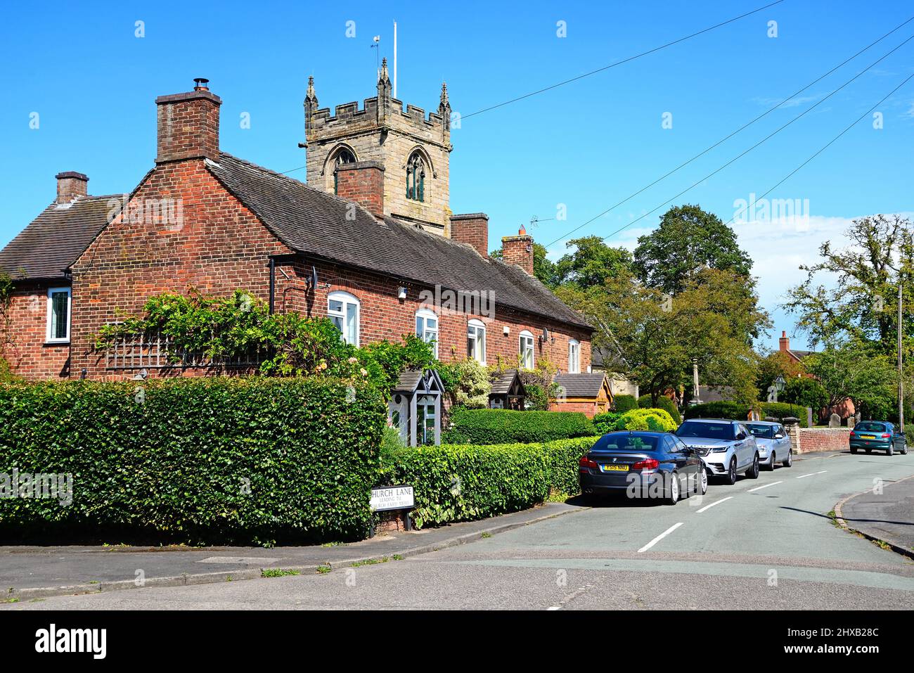 Row of traditional red brick building with All Saints Church to the
