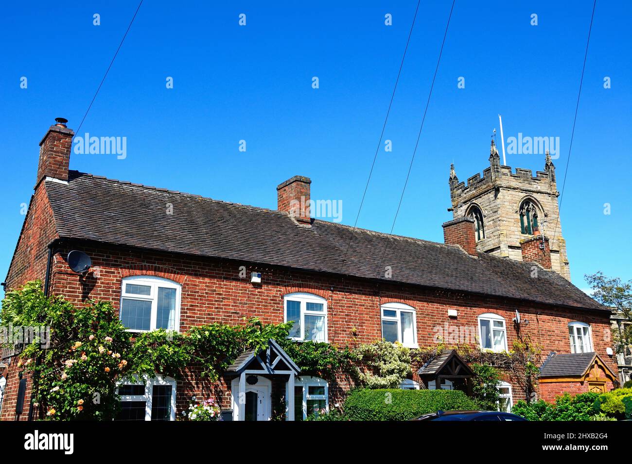 Row of traditional red brick building with All Saints Church to the
