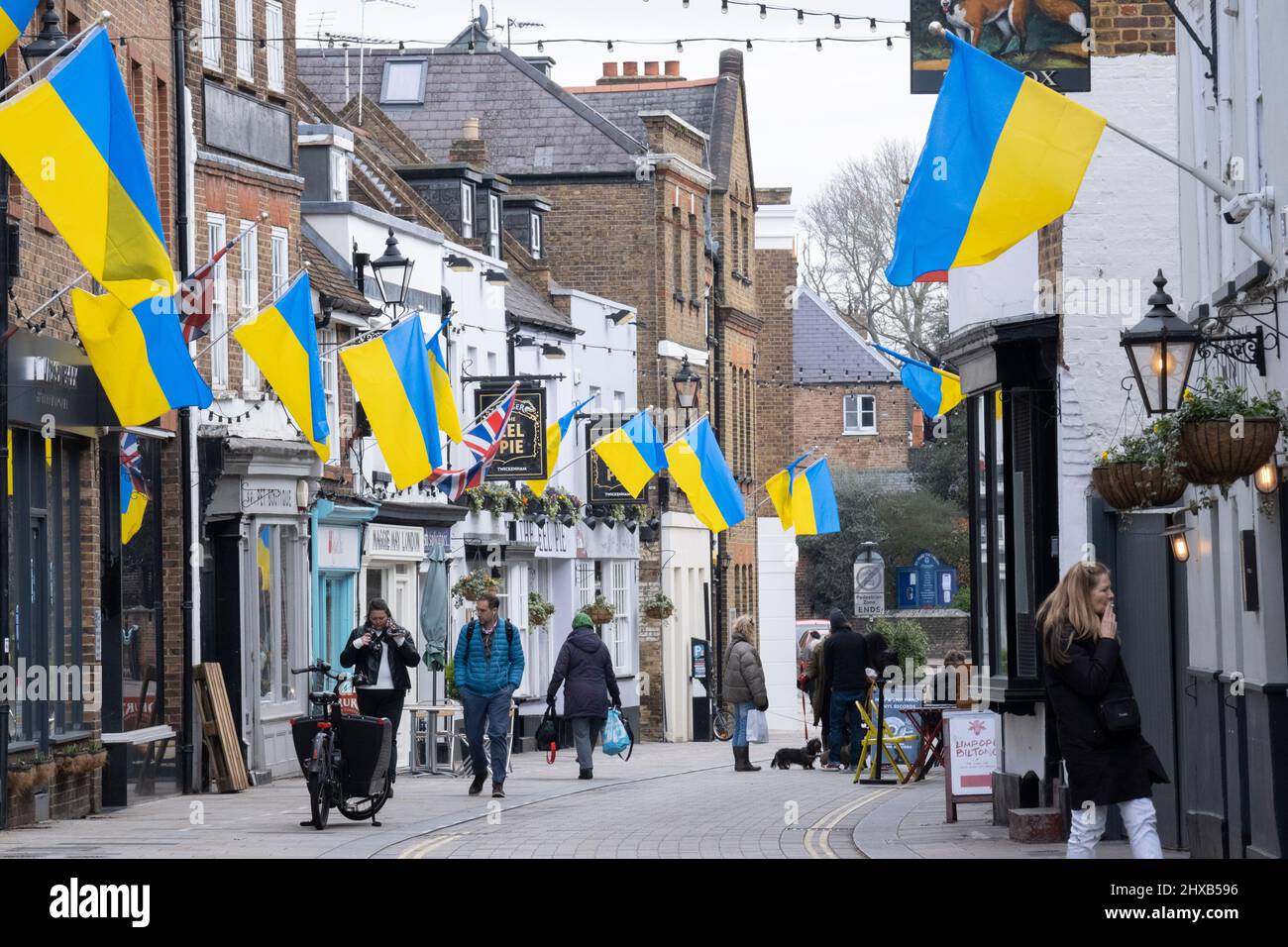 As the war in Ukraine enters its third week, Ukrainian flags hang alongside British Union Jacks above businesses in Church Street, Twickenham, on 10th March 2022, in London, England. The initiative was organised by The Church Street of Twickenham Association showing solidarity and sympathy with local Ukrainians, saying: 'Showing solidarity with our Ukrainian brothers and sisters. We feel for you and your horrific ordeal. Stay strong!' Stock Photo