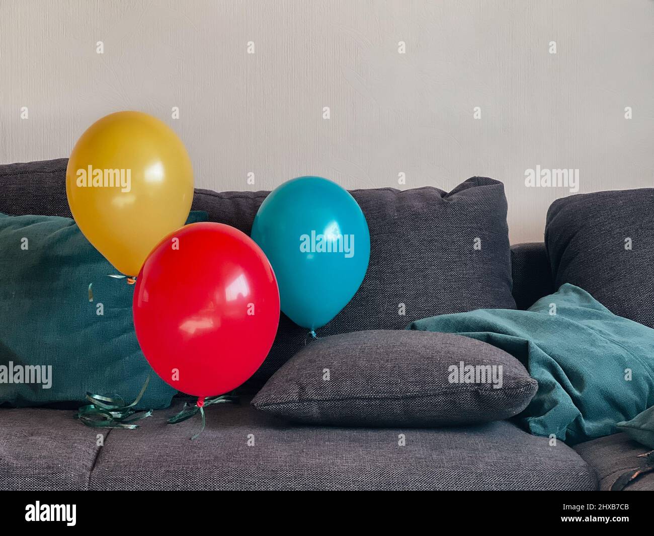 Three balloons yellow red and blue floating above the couch Stock Photo