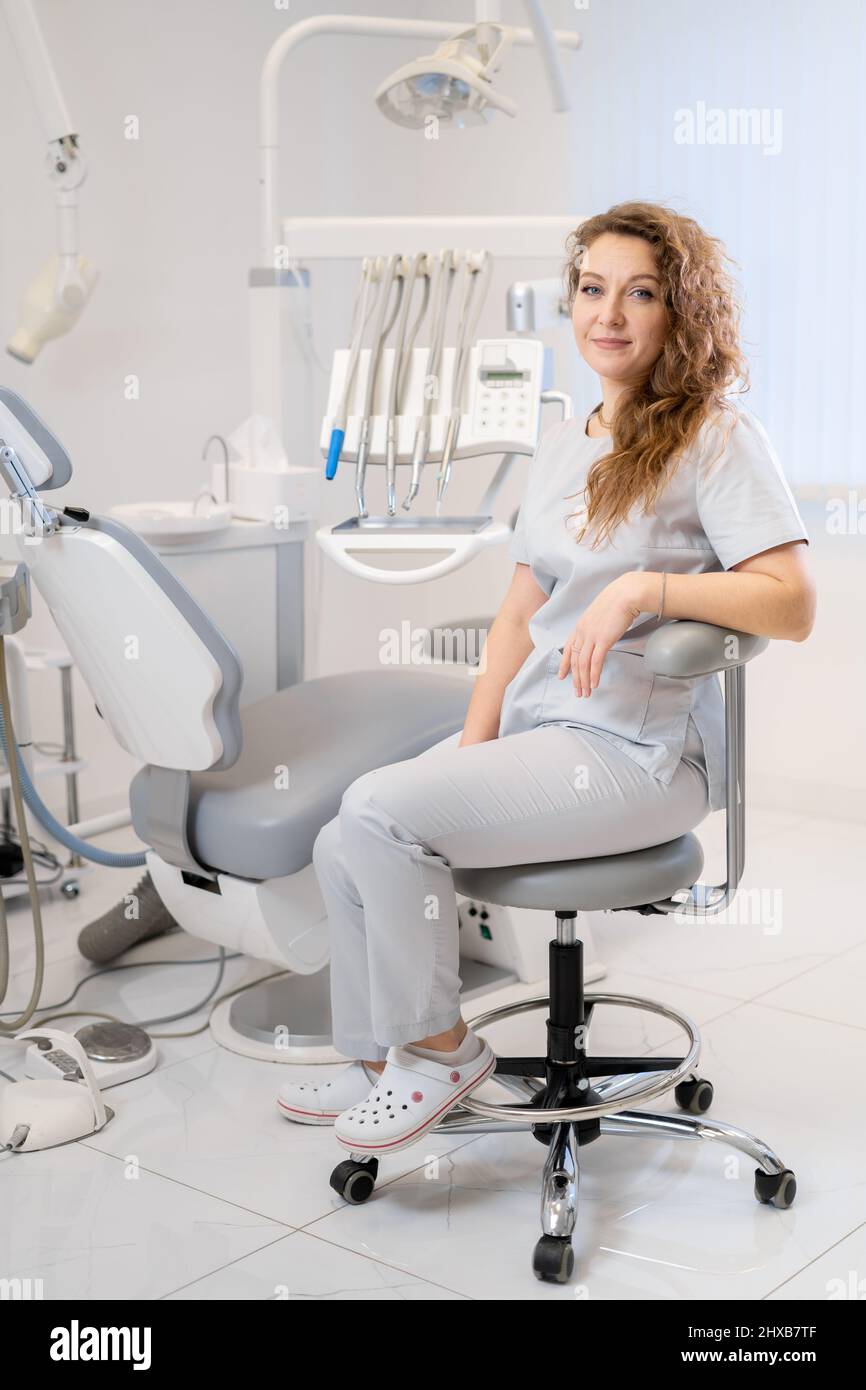 Portrait of a female dentist. She is sitting on a chair in her dentist