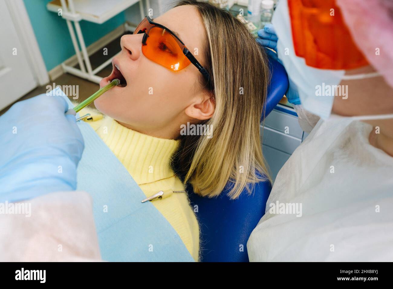 A young beautiful girl in dental glasses treats her teeth at the