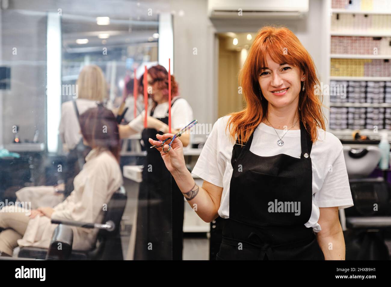 Hairdresser holding a scissor in her hand while standing in the hair