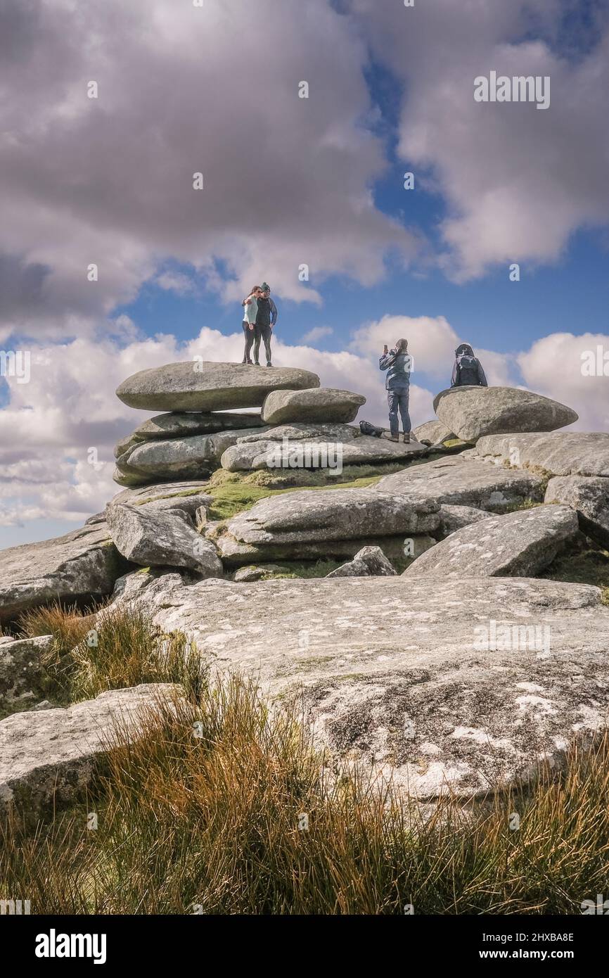 Walkers posing on a granite rock stack formed by glacial action and having their photograph taken on Stowes Hill on Bodmin Moor in Cornwall. Stock Photo