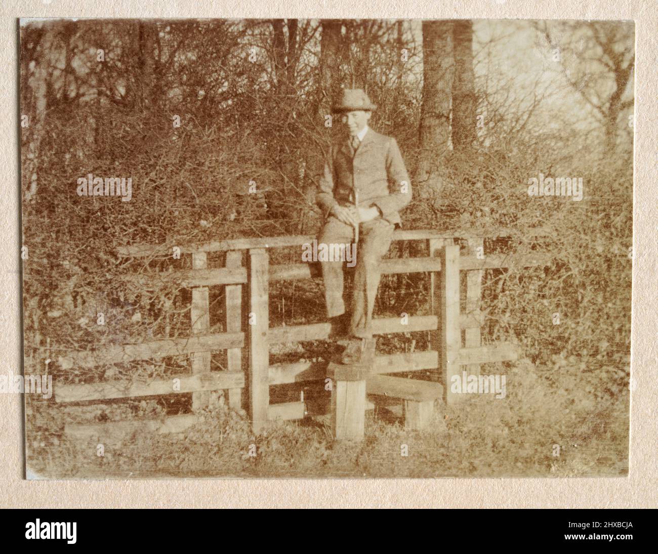 Vintage photograph of a teenage boy sitting on a stile, walking, hiking, countryside, Edwardian England 1905 Stock Photo