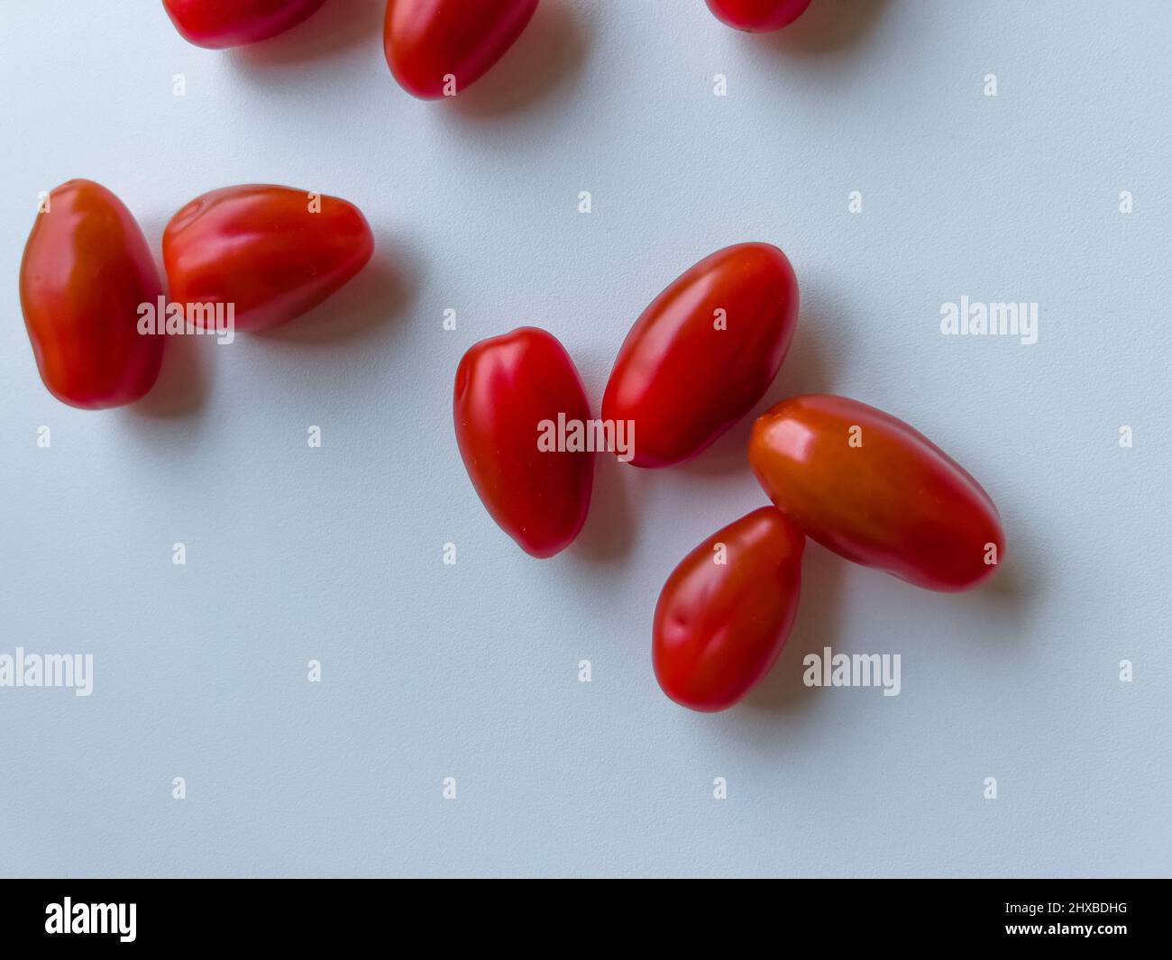 Cherry tomatoes lying on a white table Stock Photo
