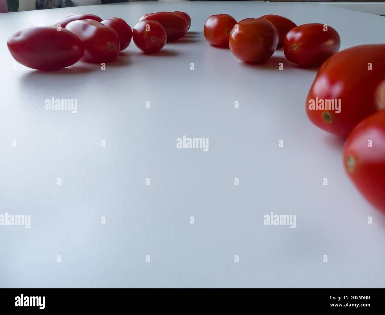 Cherry tomatoes are lying on a white table, space for a text Stock Photo