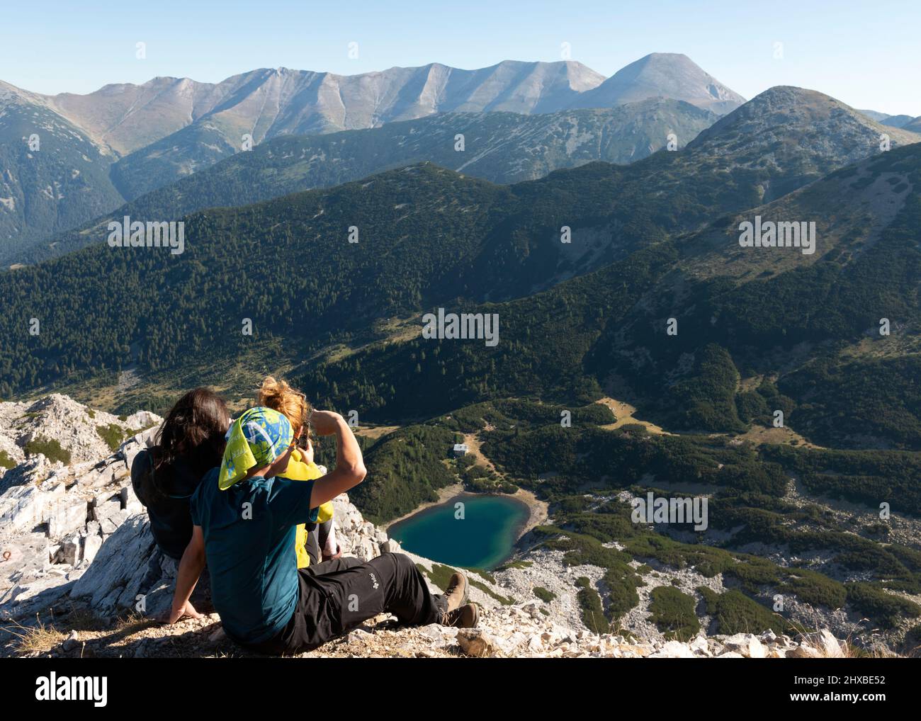 Hikers on Sinanitsa Peak at 2516m overlooking Sinanitsa glacial lake and Vihren Mountain Ridge in Pirin Mountain, Bulgaria, Eastern Europe, Balkans Stock Photo