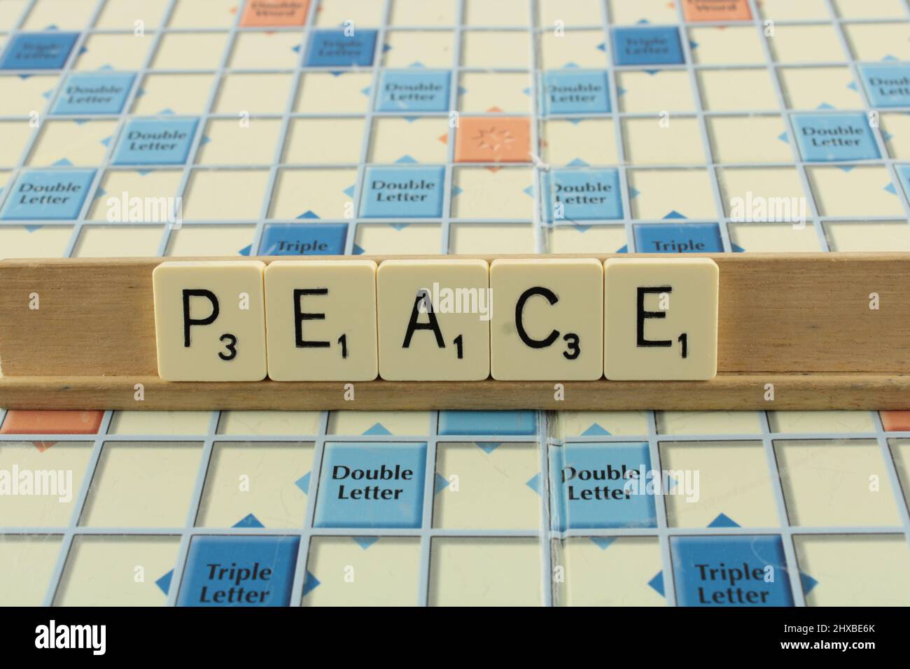 The word Peace in white tiles for emphasis on a scrabble board. Hope for peace concept Stock Photo