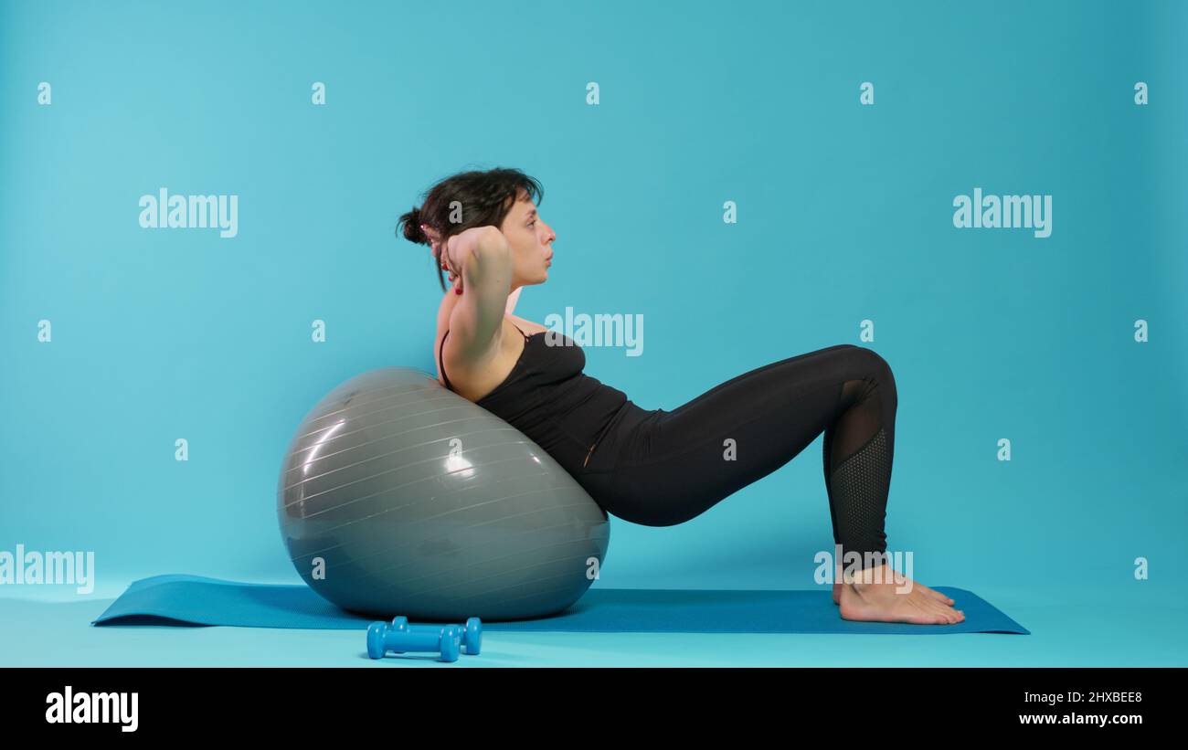 Athletic person doing physical effort on fitness toning ball, training