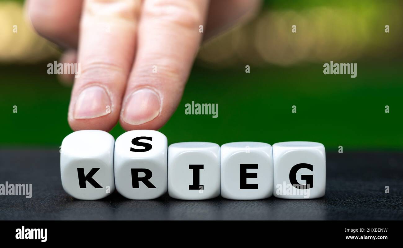 Hand turns dice and changes the German word 'Krieg' (war) to 'Sieg' (victory). Stock Photo
