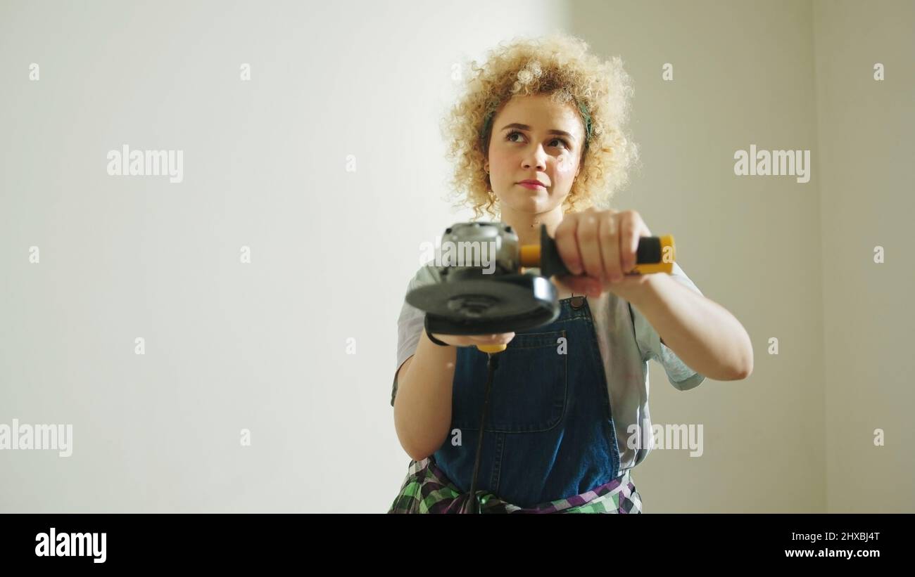 Pensive girl holding angle disc grinder and thinking about new DIY Project. High quality photo Stock Photo