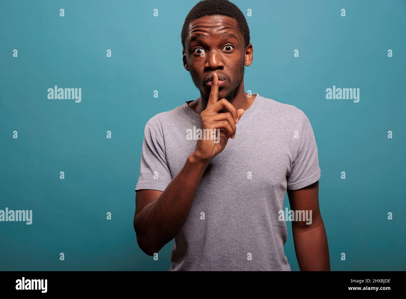 Male model doing hush sign with finger over lips to keep secret about