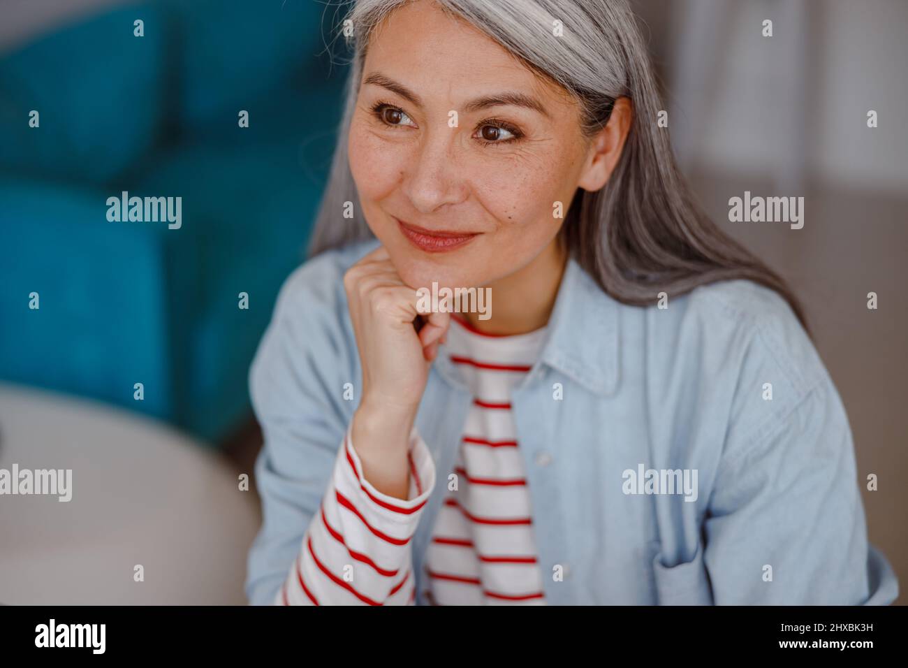 Joyful woman propping up head with hand and smiling Stock Photo