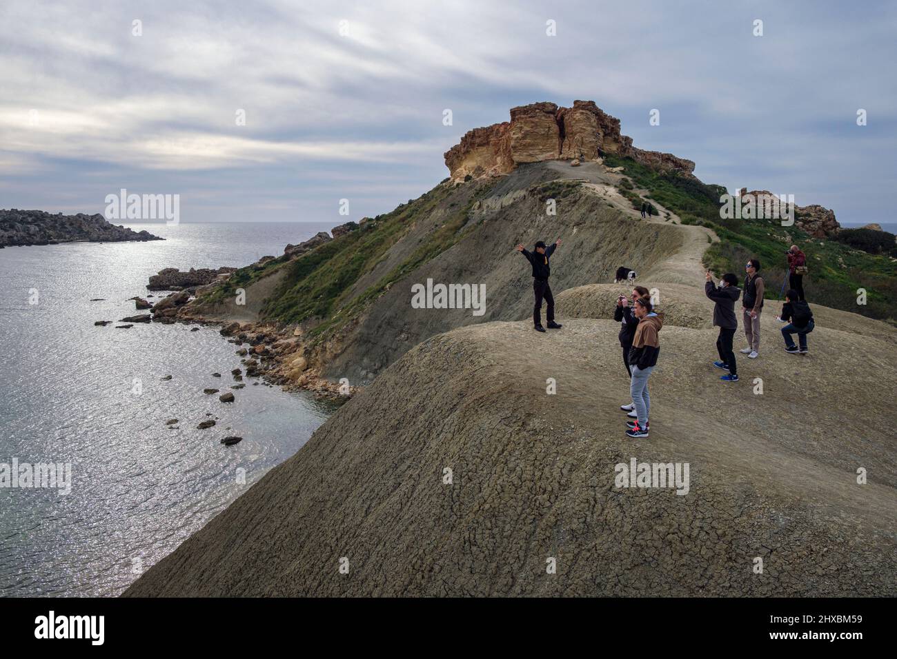 Tourists taking photographs on top of the clay cliffs at Qarraba Bay, Malta Stock Photo