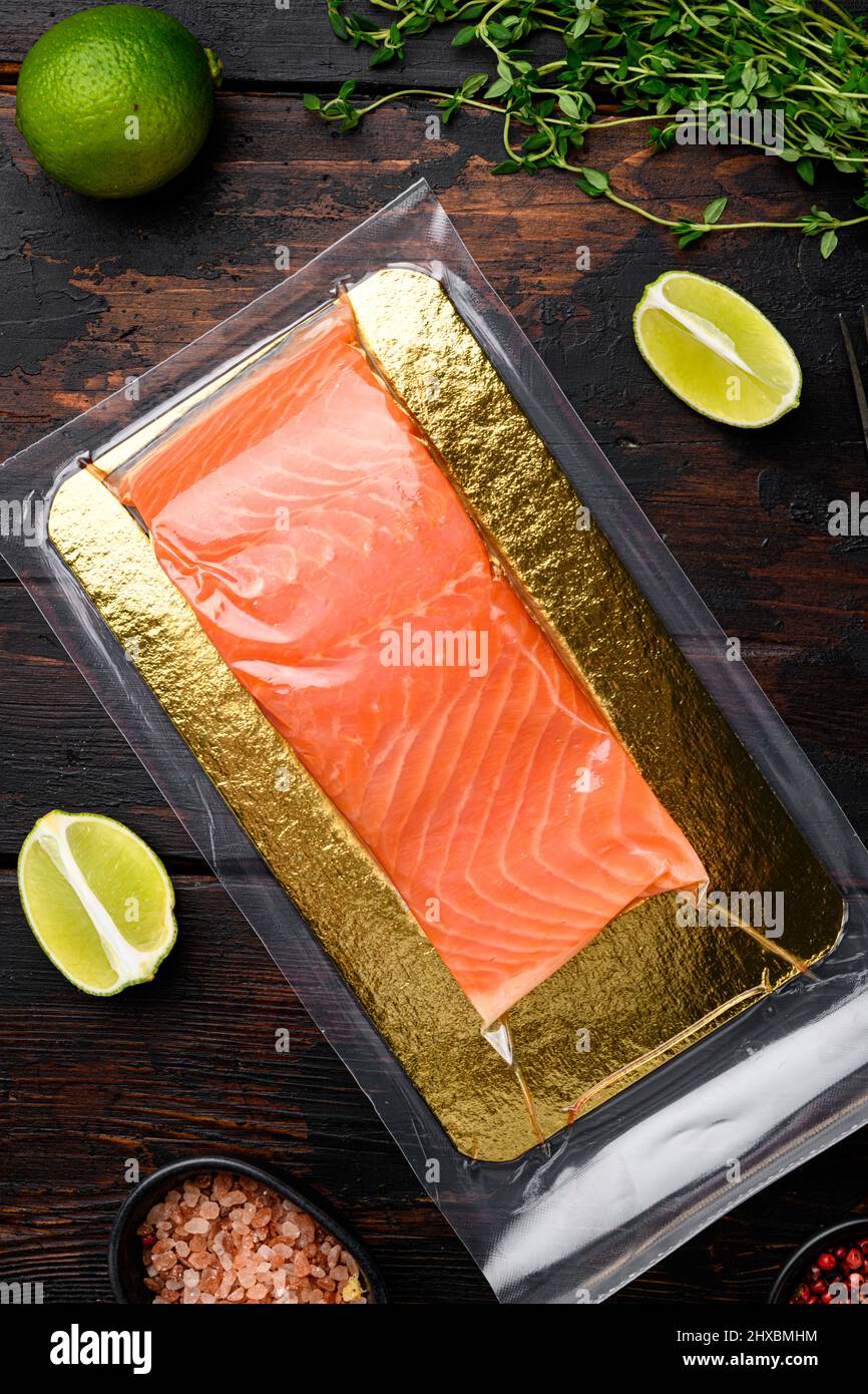 Vacuum packed salmon portion fillet set, with herbs, on old dark wooden ...