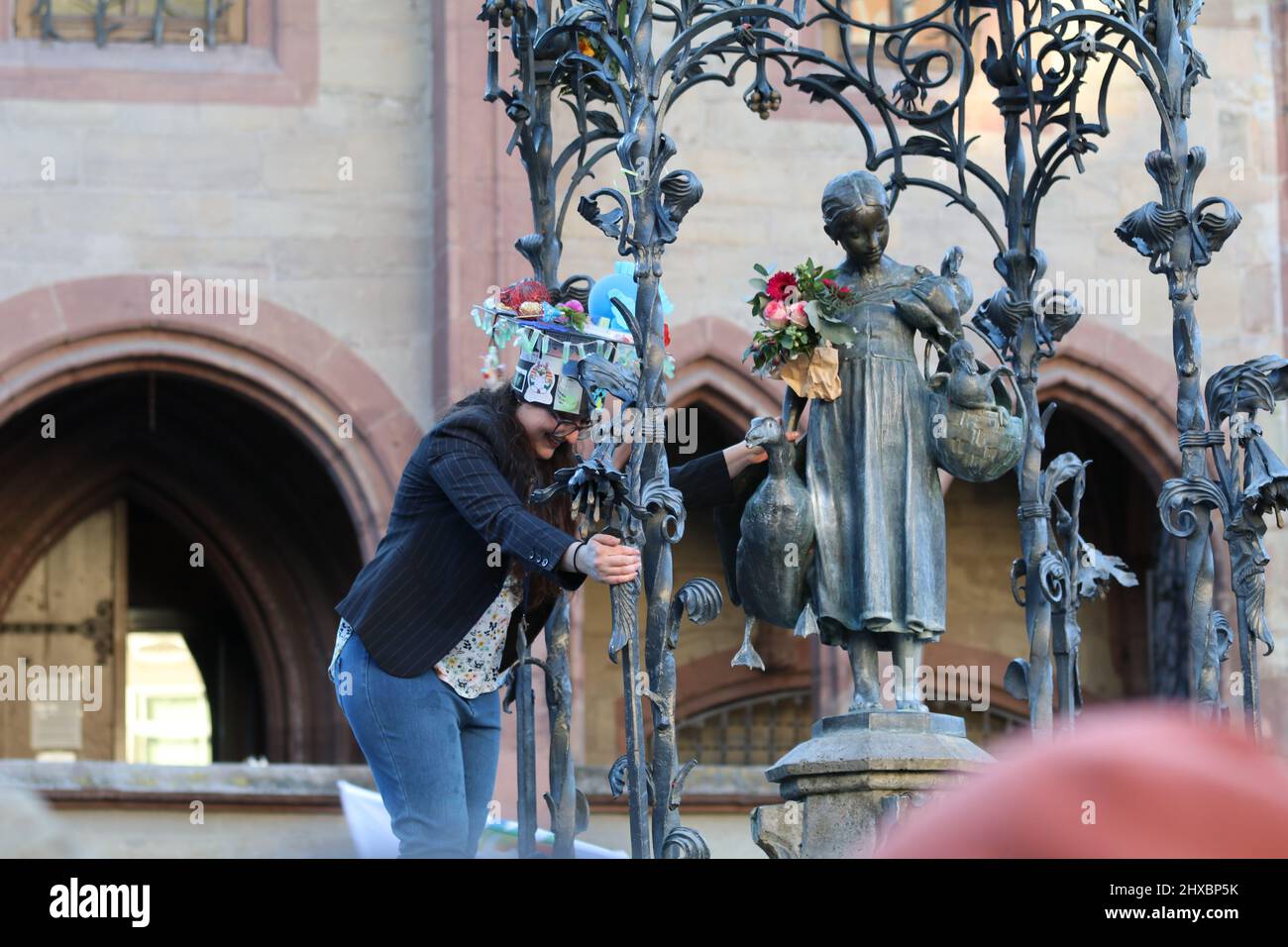 March 8, 2022, GÃ¶ttingen, Lower Saxony, Germany: PhD graduate woman celebrate on GÃ¤nseliesel statue on the occasion of International Women's Day in GÃ¶ttingen, Germany. By tradition PhD graduates climb Gaenseliesel fountain in centeral of GÃ¶ttingen city, kiss the goose girl and give her flowers. (Credit Image: © Tubal Sapkota/Pacific Press via ZUMA Press Wire) Stock Photo