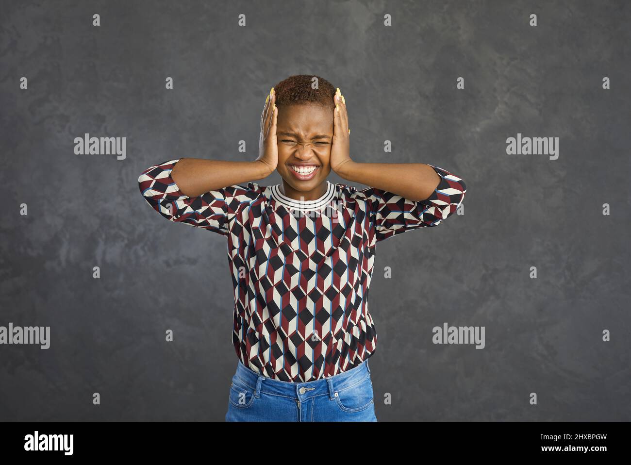 Stressed woman covering her ears with her hands protecting herself from a loud noise Stock Photo