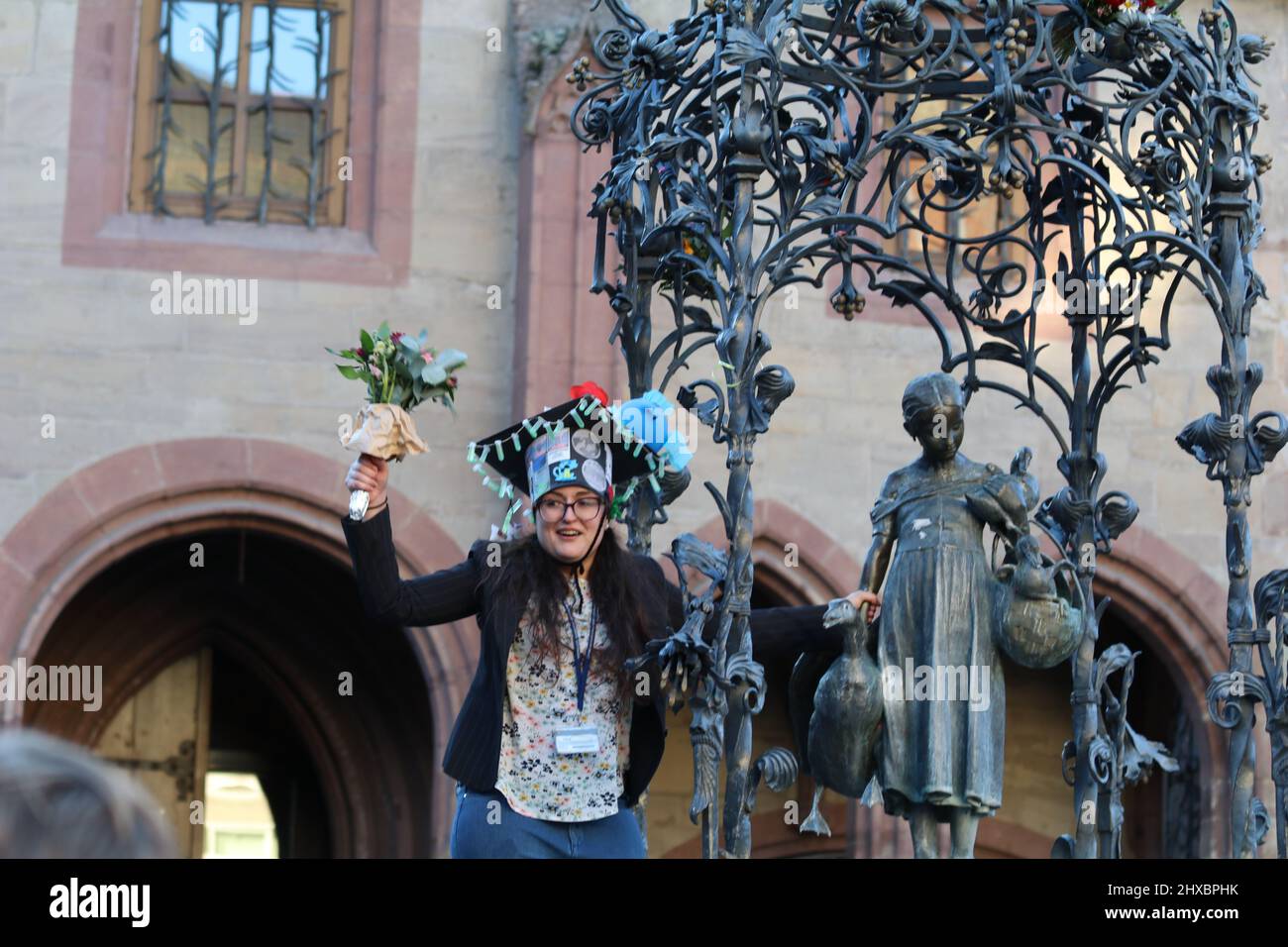 March 8, 2022, GÃ¶ttingen, Lower Saxony, Germany: PhD graduate woman celebrate on GÃ¤nseliesel statue on the occasion of International Women's Day in GÃ¶ttingen, Germany. By tradition PhD graduates climb Gaenseliesel fountain in centeral of GÃ¶ttingen city, kiss the goose girl and give her flowers. (Credit Image: © Tubal Sapkota/Pacific Press via ZUMA Press Wire) Stock Photo