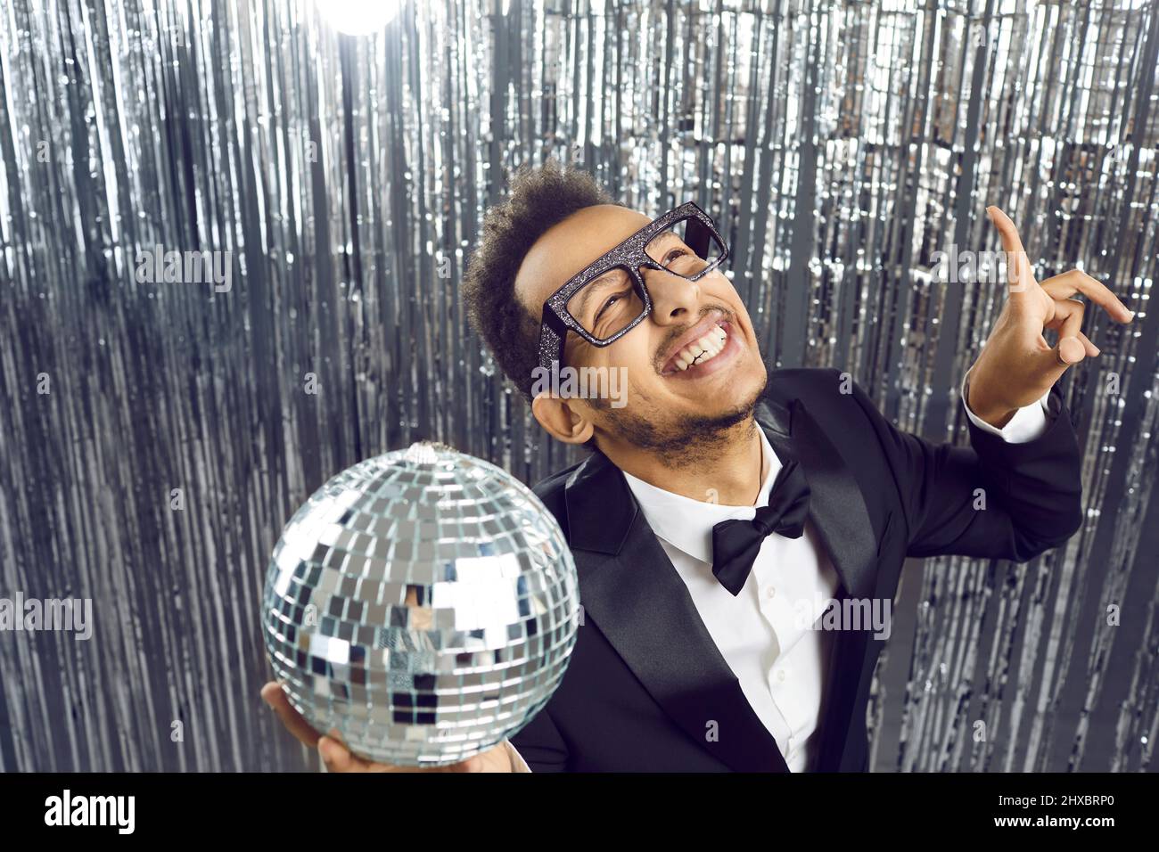 Happy funny young black guy in tuxedo and glasses dancing and having fun at party Stock Photo