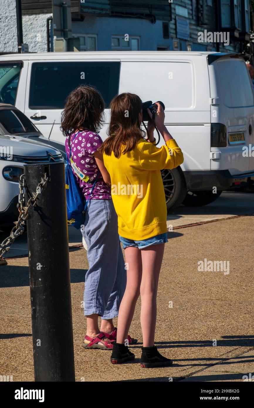 Two teenage girls take photos of the busy Hythe on the River Chelmer in Maldon, Essex,UK Stock Photo