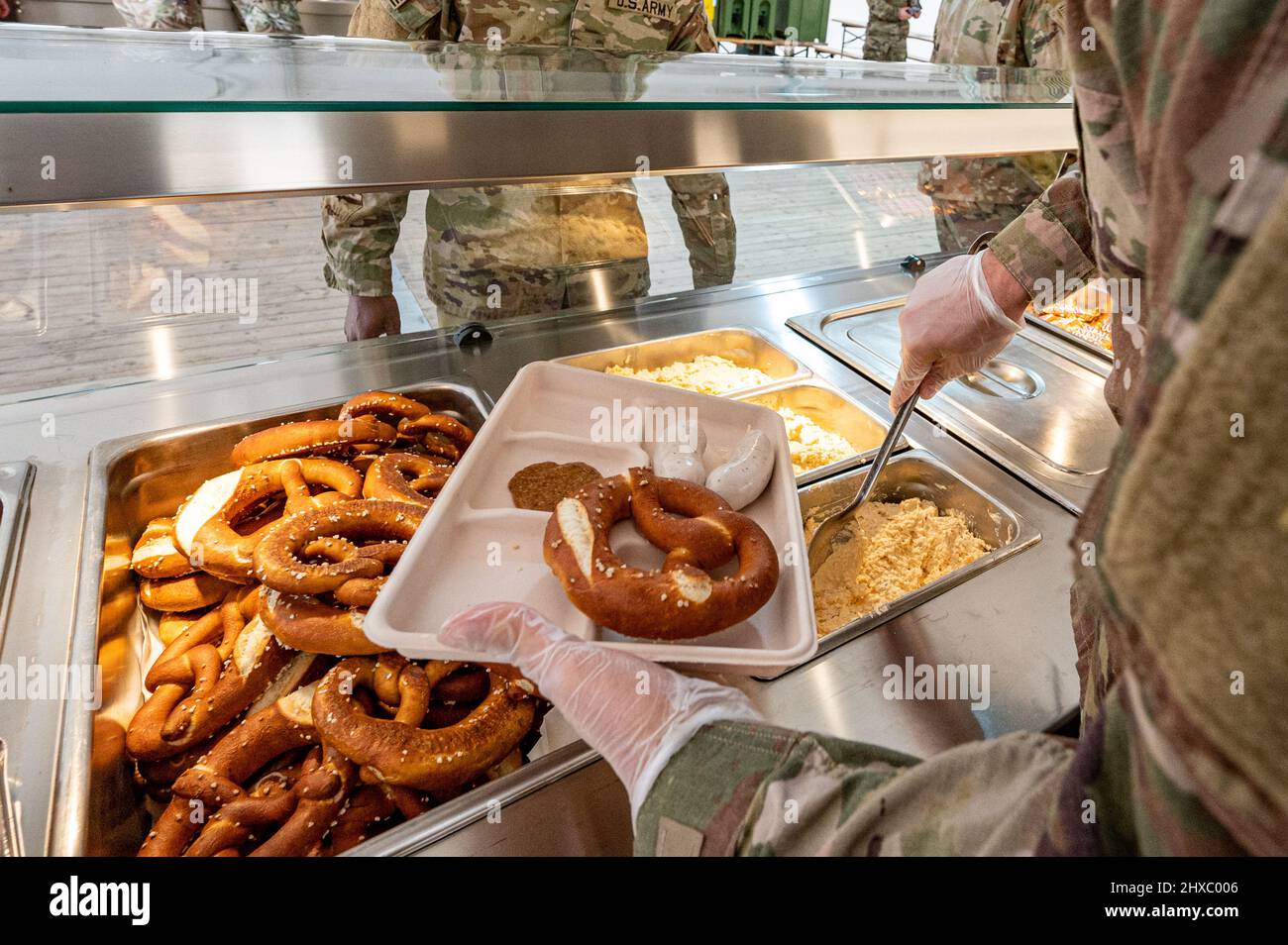 Grafenwohr, Germany. 11th Mar, 2022. 11 March 2022, Bavaria, Grafenwöhr: U.S. soldiers are given trays of food in a tent on the grounds of the Grafenwoehr military training area - each with Weißwurst, sweet mustard, Obatzda and a pretzel. With the traditional Weißwurst breakfast, Bavaria's Minister President Söder welcomed around 4,000 U.S. Army soldiers to the Upper Palatinate. Photo: Armin Weigel/dpa Credit: dpa picture alliance/Alamy Live News Stock Photo