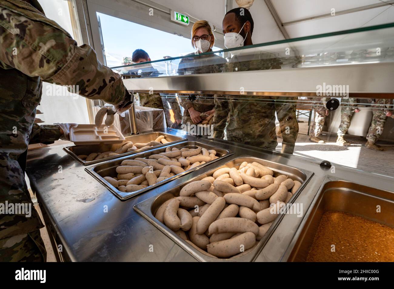 Grafenwohr, Germany. 11th Mar, 2022. 11 March 2022, Bavaria, Grafenwöhr: U.S. soldiers are served a Weißwurst breakfast in a tent on the grounds of the Grafenwoehr military training area. With the traditional Weißwurst breakfast, Bavaria's Prime Minister Söder welcomed around 4,000 soldiers of the US Army to the Upper Palatinate. Photo: Armin Weigel/dpa Credit: dpa picture alliance/Alamy Live News Stock Photo