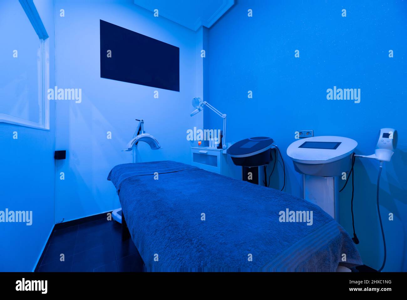 Cabin with stretcher and equipment for dermo-aesthetic treatments with dim blue light Stock Photo