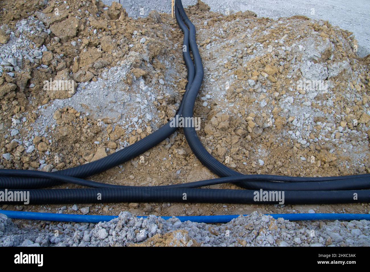 Black corrugated plastic drainage pipes laying in a ditch at a