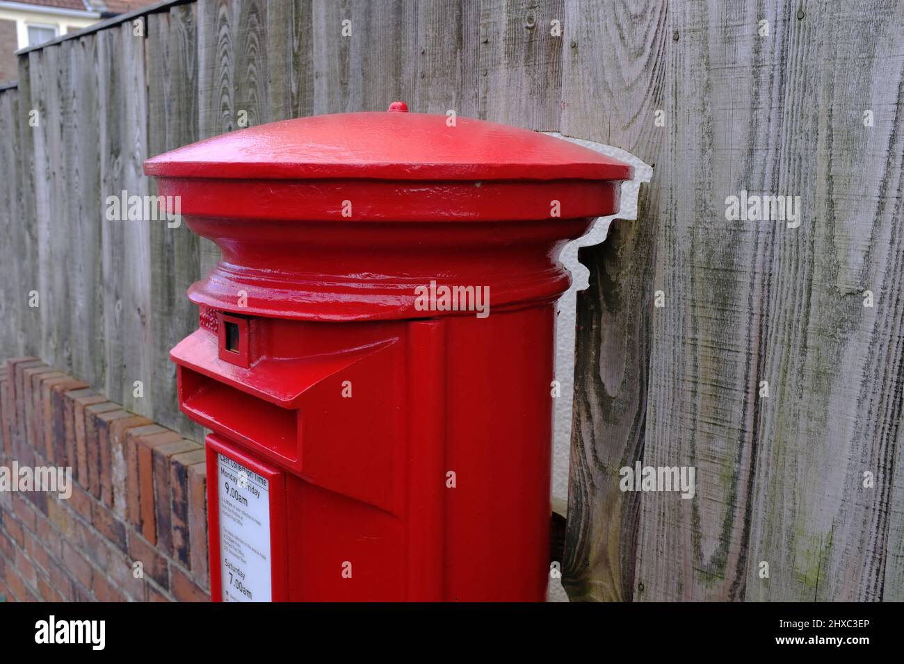 A post box very close to a fence. Stock Photo