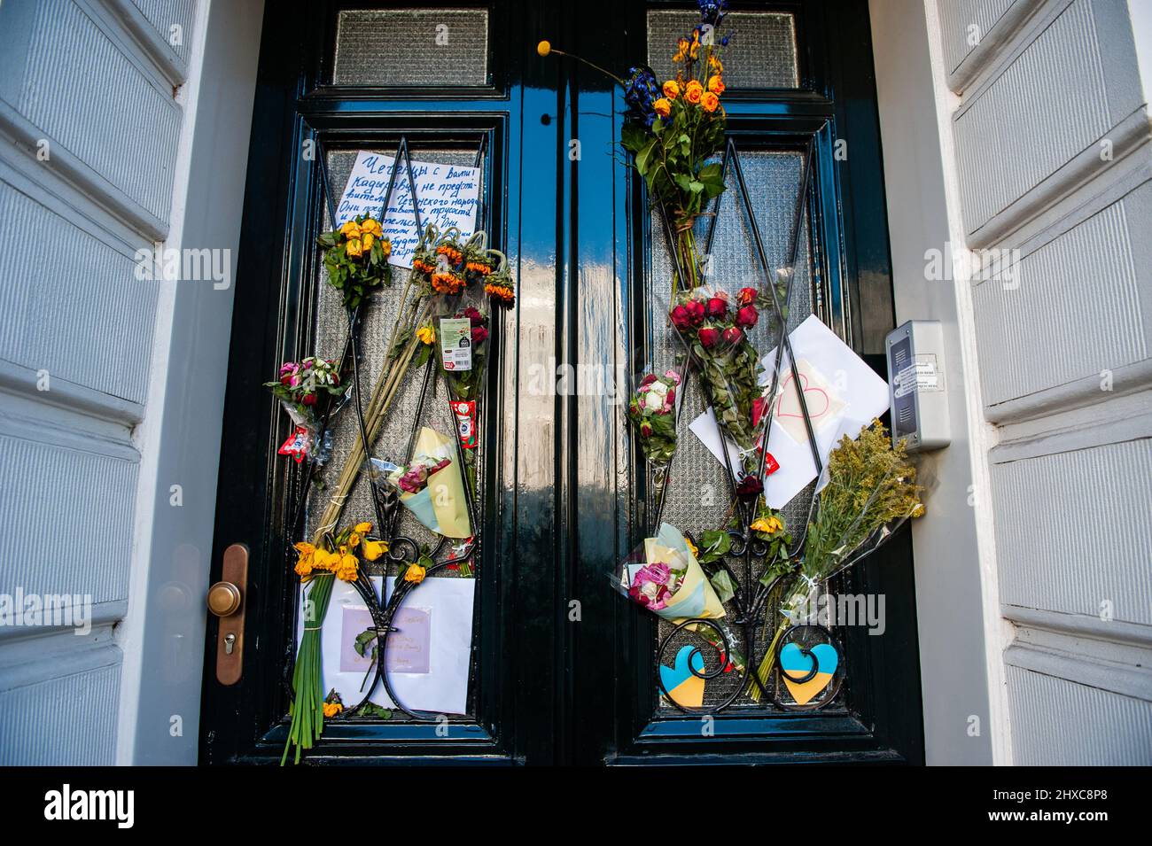 The door of the Embassy of Ukraine in The Netherlands decorated with flowers and placards in support of Ukraine and against war. Since Putin's invasion of Ukraine started two weeks ago, the facade of the Ukrainian Embassy in The Hague has been decorated with flowers, Ukrainian flags, placards, and messages in support of the Ukrainian people. At least 1.4 million people have left Ukraine since Russia invaded last month and around 516 civilians have been killed and 908 injured in the fighting. U.N. monitors said 37 children have been killed and 50 injured since the start of the conflict. Stock Photo