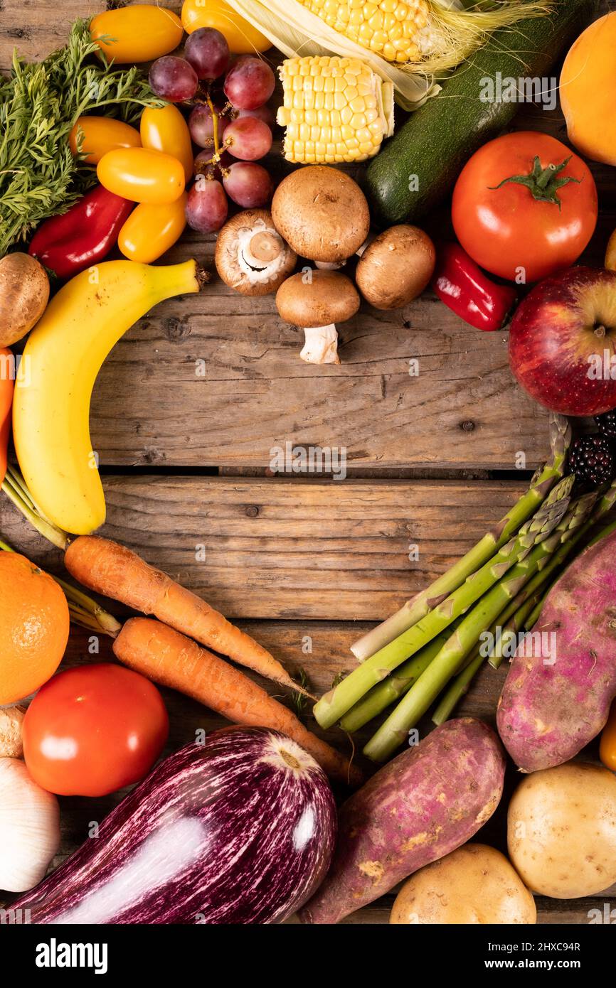 Directly above shot of various vegetables and fruits with empty heart shape made on wooden table Stock Photo
