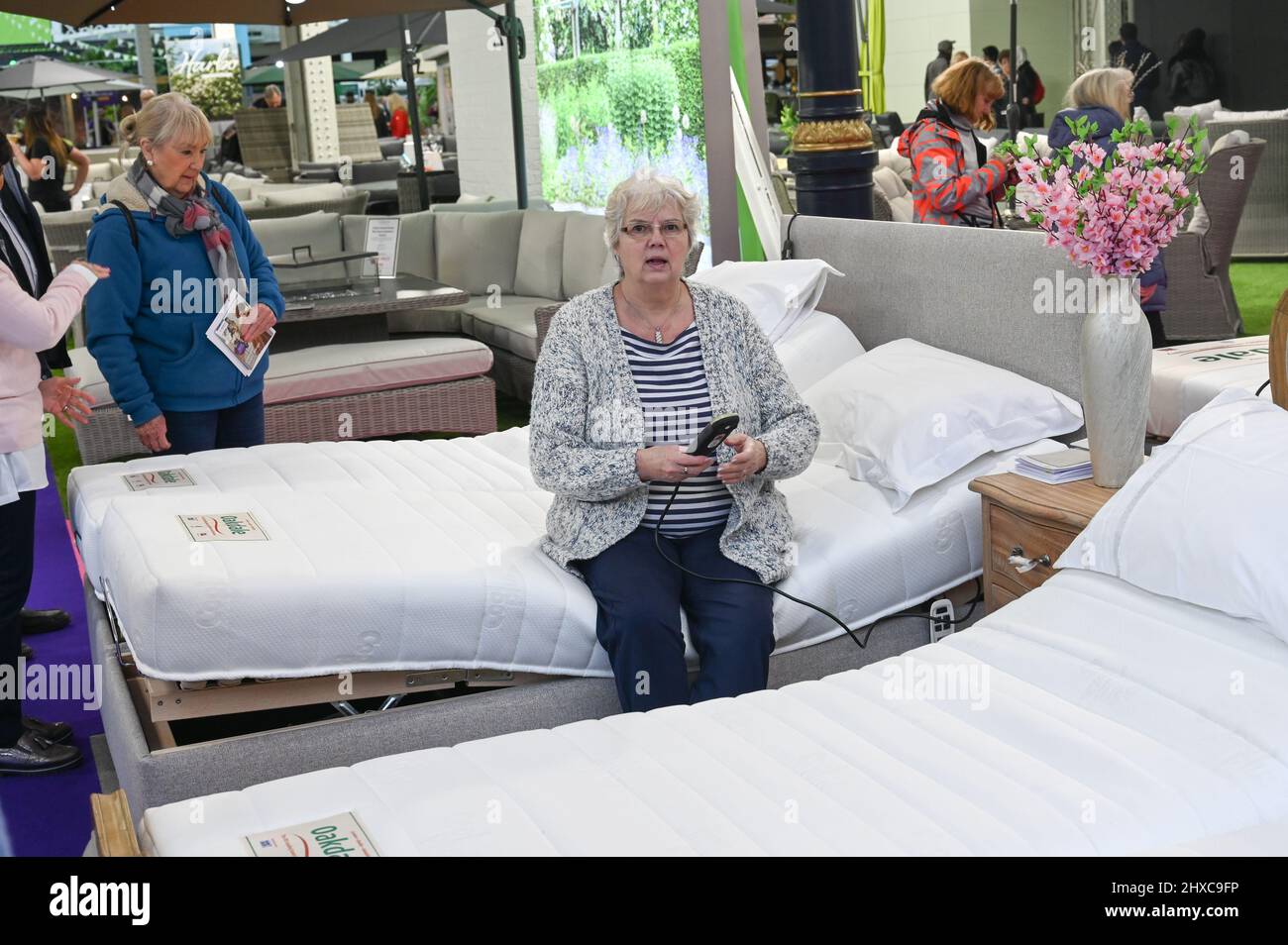 London, UK. 11 March 2022. A lady sitting on a bed see if is comfortable at Ideal Home Show 2022 at Olympia London. Credit: Picture Capital/Alamy Live News Stock Photo