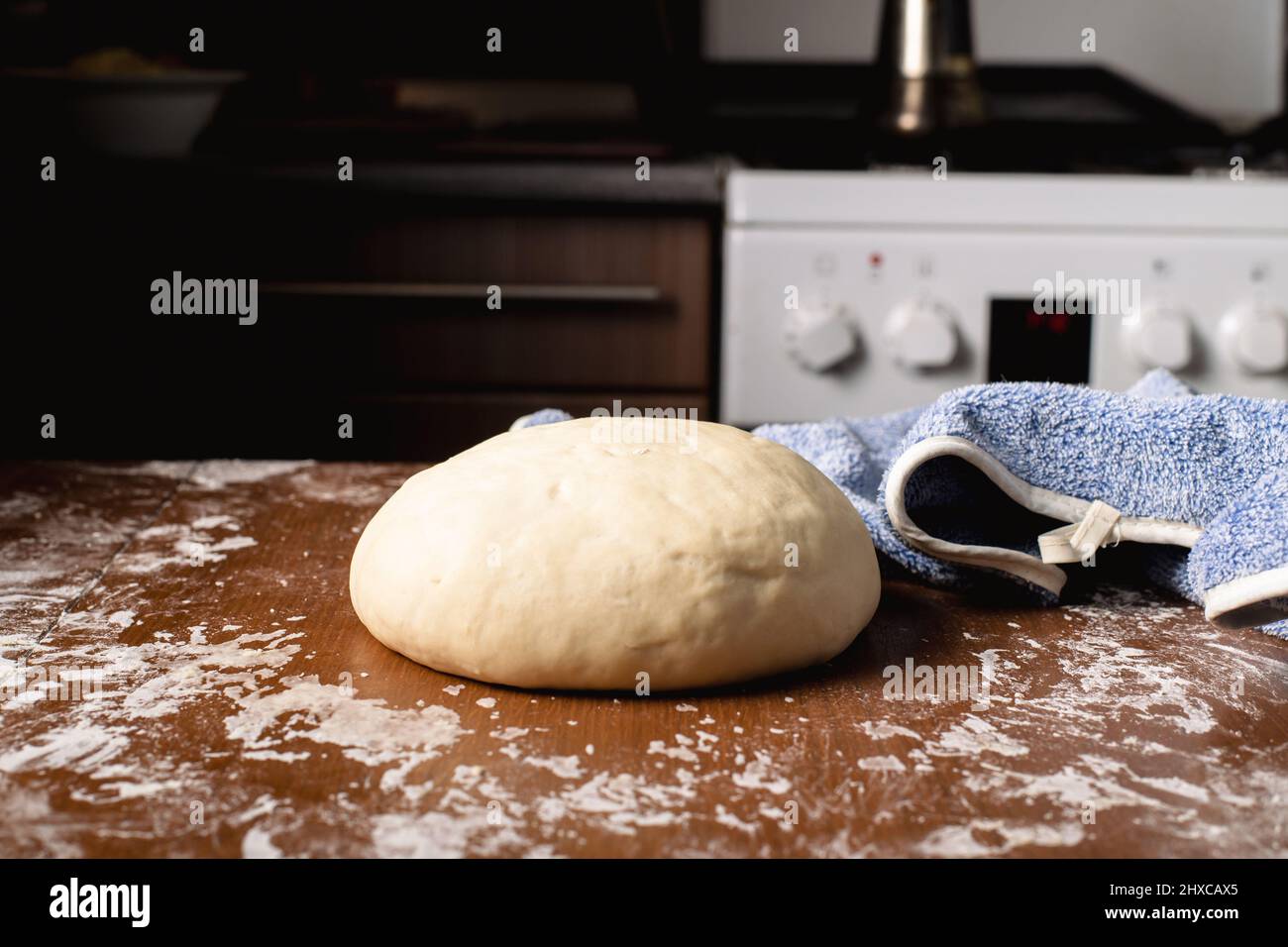 The finished kneaded round dough lies on the kitchen table at home ...
