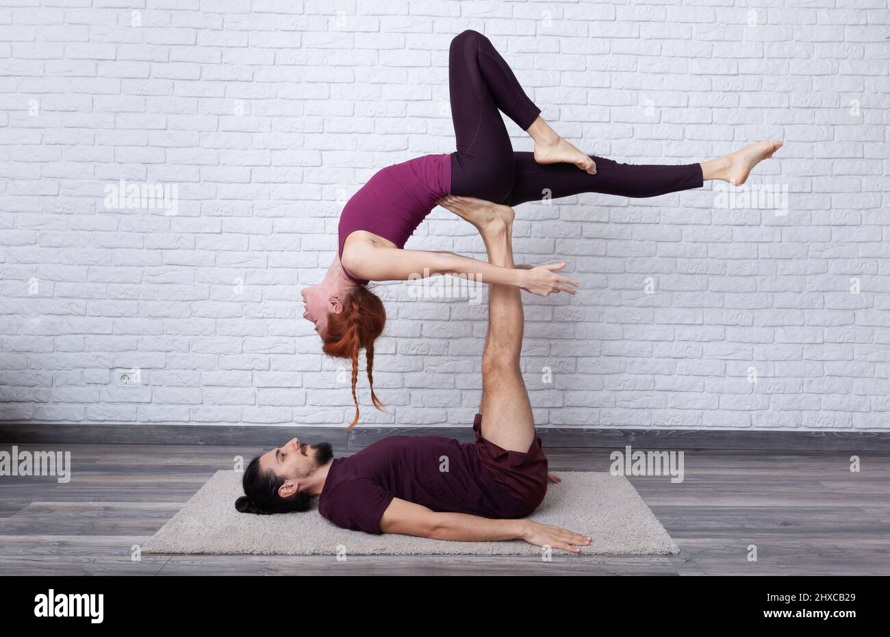 young couple having fun at home with some acro yoga poses in different places 2HXCB29