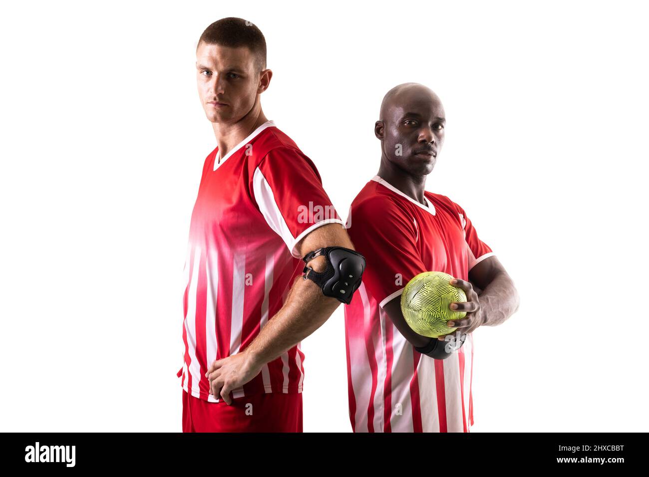 Portrait of confident multiracial handball players standing back to back against white background Stock Photo