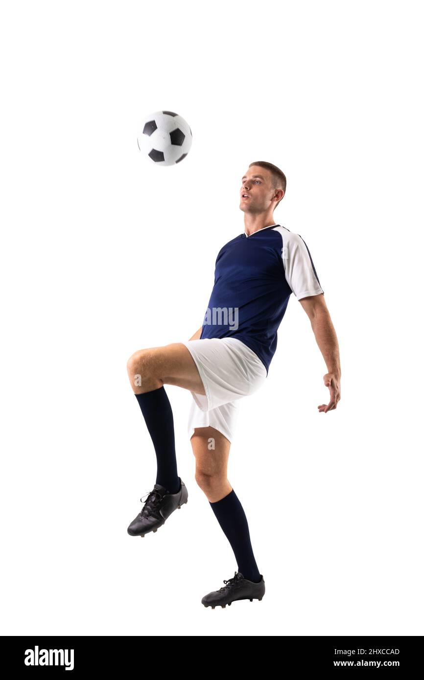Full length of skilled caucasian male player kicking ball against white background Stock Photo
