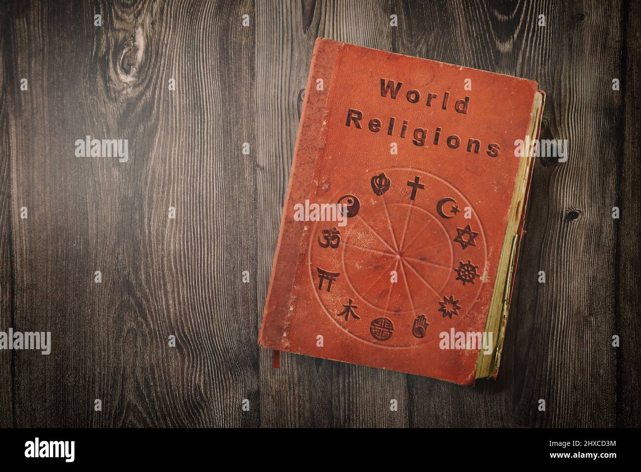 World religions book with religious symbols printed on wooden table. Top view. Stock Photo